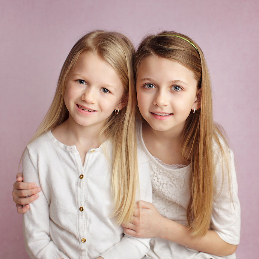Young sisters on pink backdrop