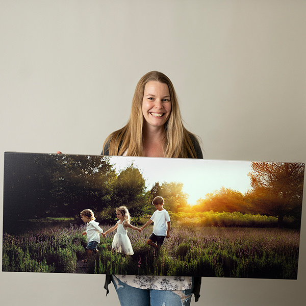 Family photographer Kelly Rawlinson holds large canvas made for client