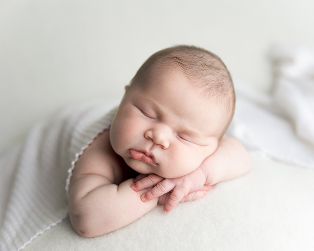 Sleeping baby in professional newborn photograph styled in soft white