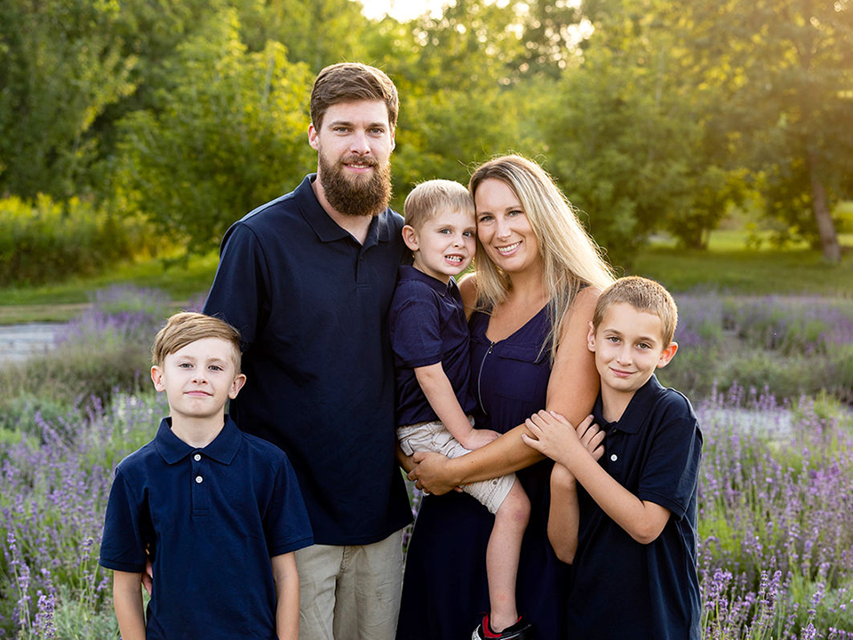 An image of a family with 3 boys standing in a lavender field