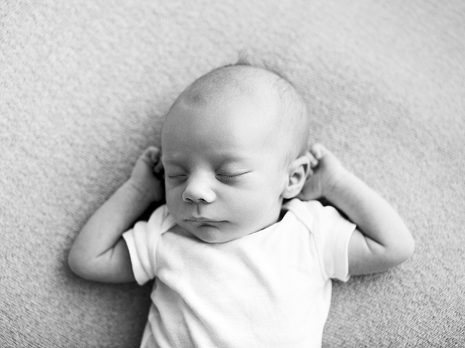 Newborn baby relaxed with arms behind head